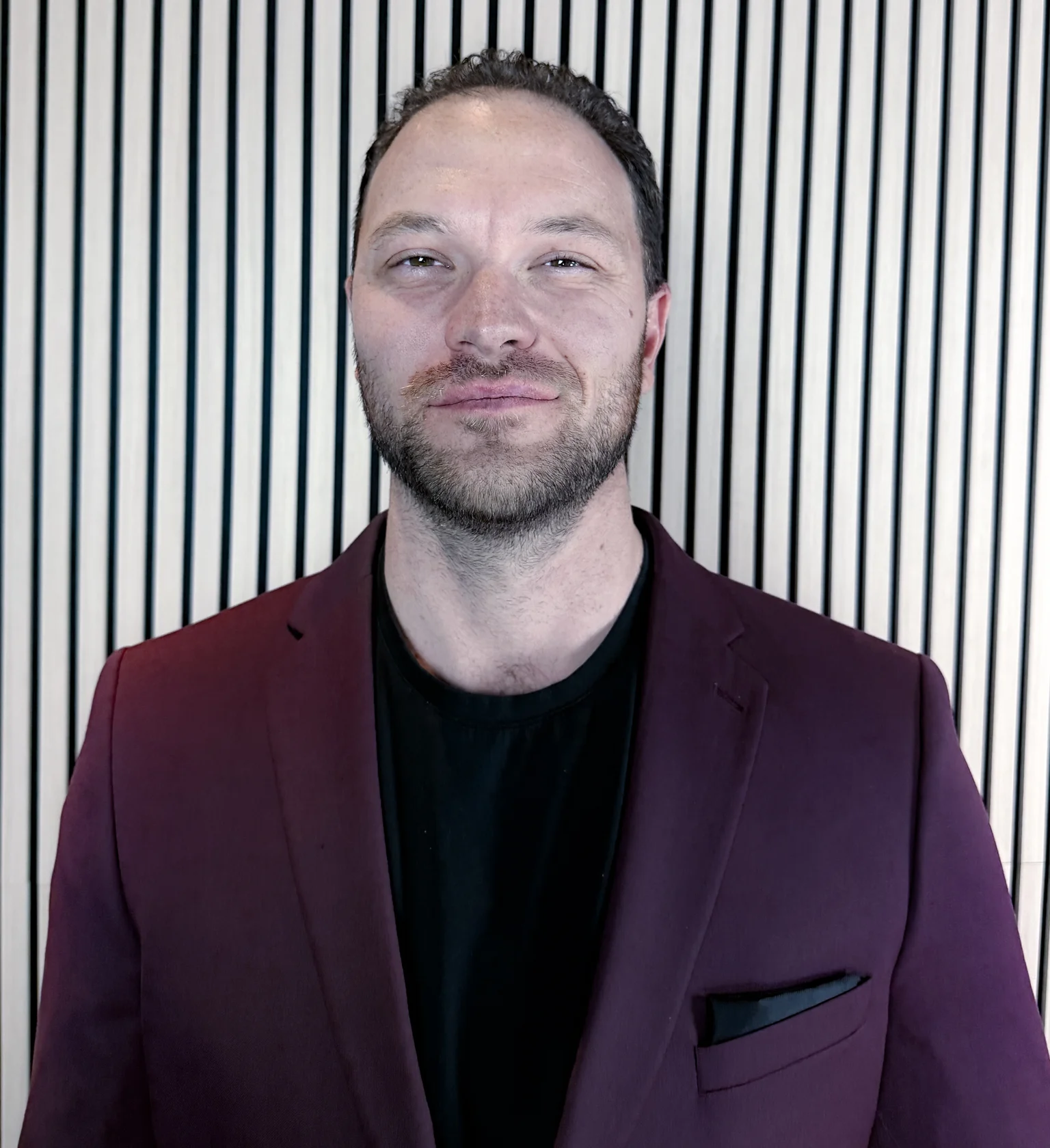 Portrait of Jason Reid, licensed advisor, in a burgundy blazer and black t-shirt